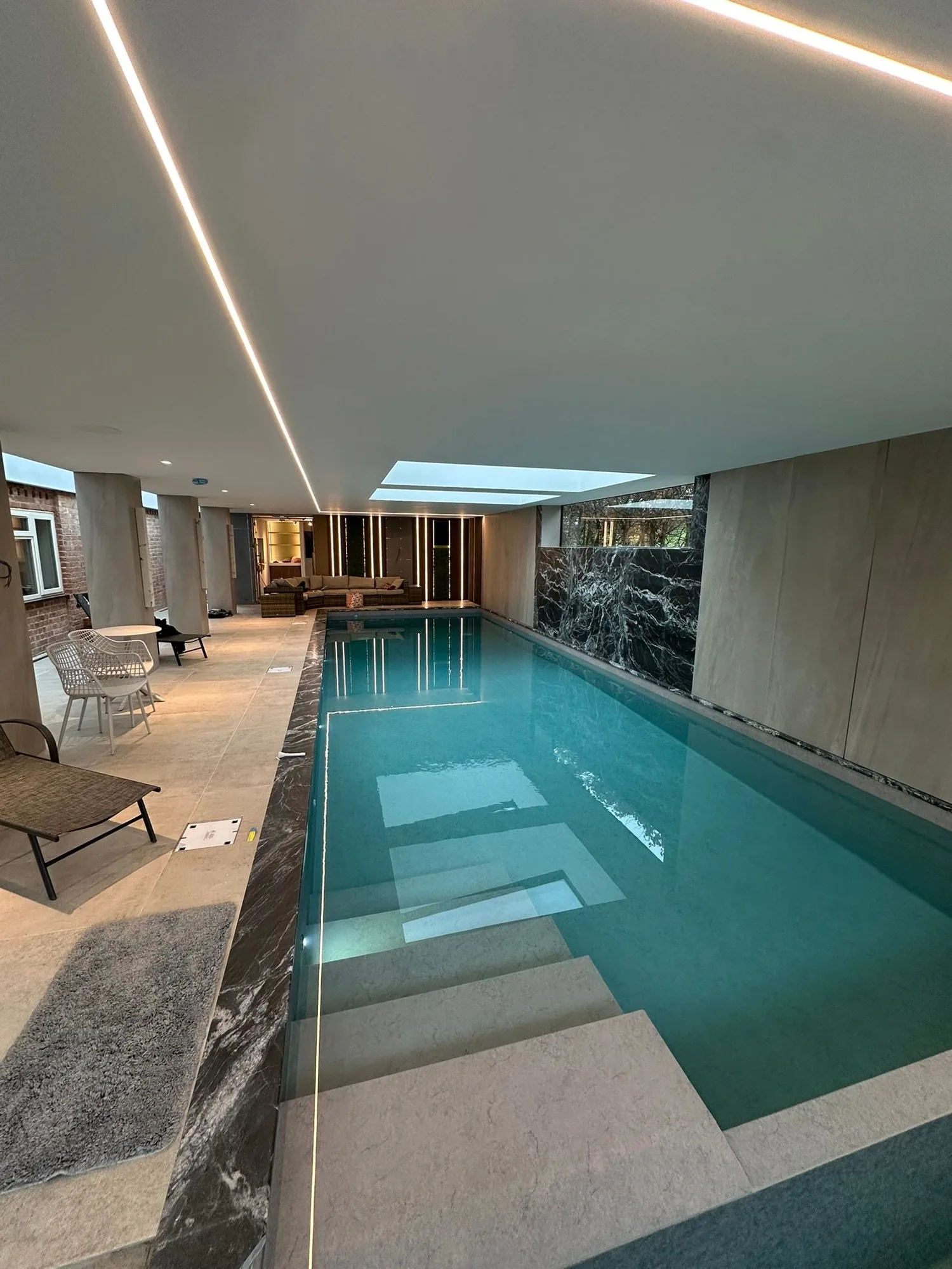Indoor swimming pool with LED lit ceiling and stone finishes, heated by an HES air source heat pump installation